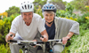 A smiling woman and a man riding their bicycles along wooded trails